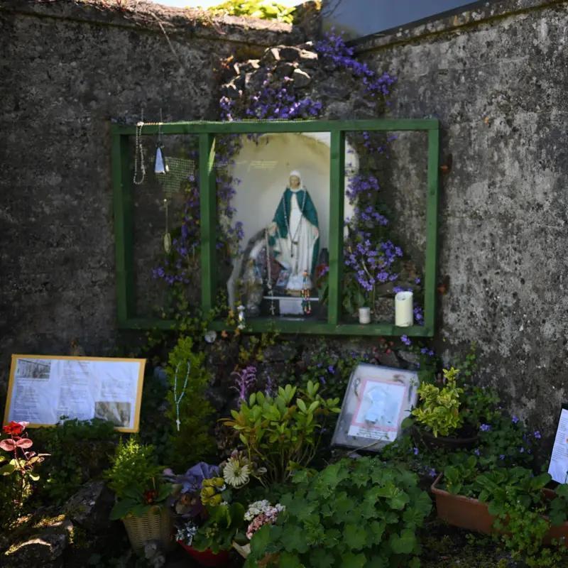 Grota su Mergelės Marijos figūrėle sode virš tariamos masinio kapo vietos --